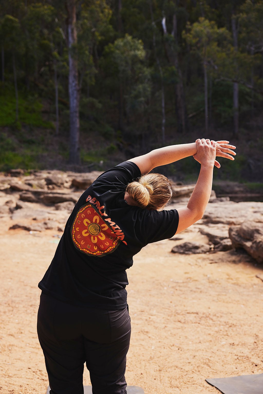 Participant standing in a dry gorge with red rocks surrounding him practicing a yoga shape